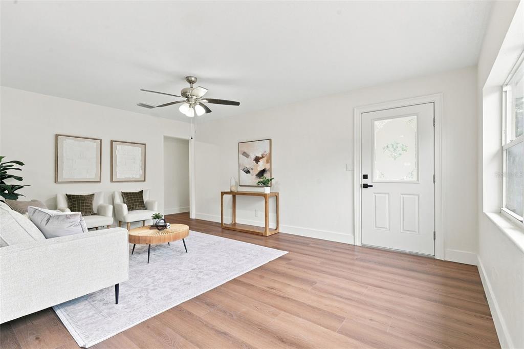 A bright living room features light wood-look flooring, white walls, and a ceiling fan — 2506 DELANEY AVENUE, ORLANDO, FL