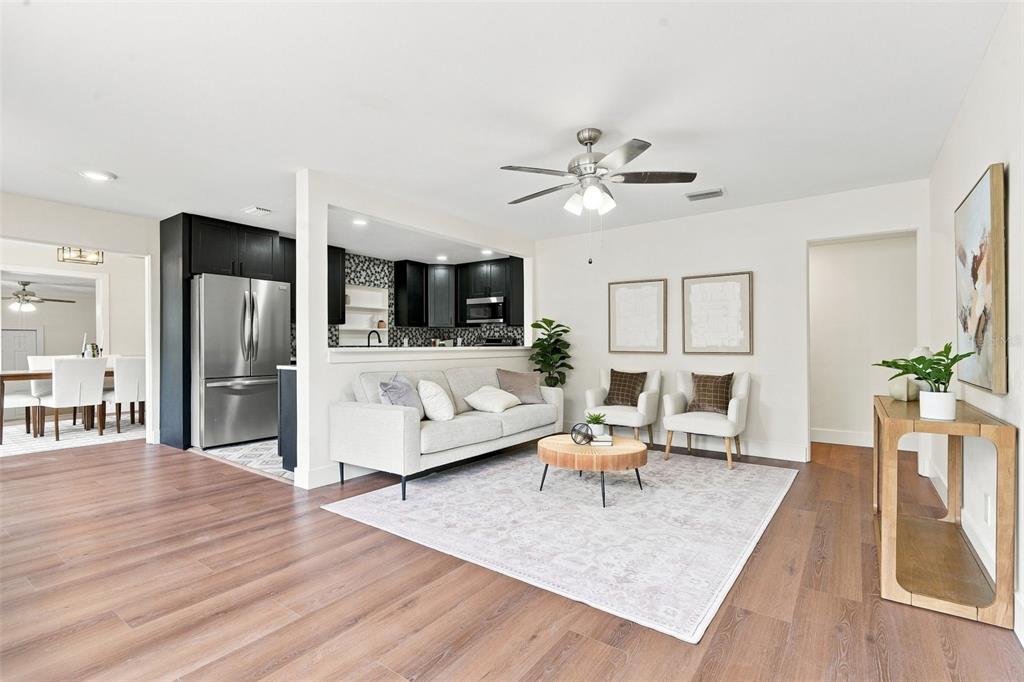 A living room with wood-look flooring, a light-colored sofa, and an open kitchen pass-through — 2506 DELANEY AVENUE, ORLANDO, FL