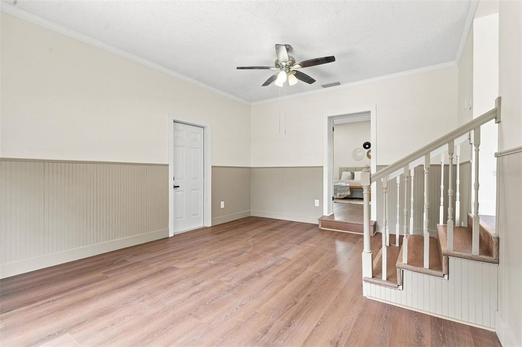 A room with wood-look flooring, wainscoting, a ceiling fan, and a staircase with wooden treads — 2506 DELANEY AVENUE, ORLANDO, FL