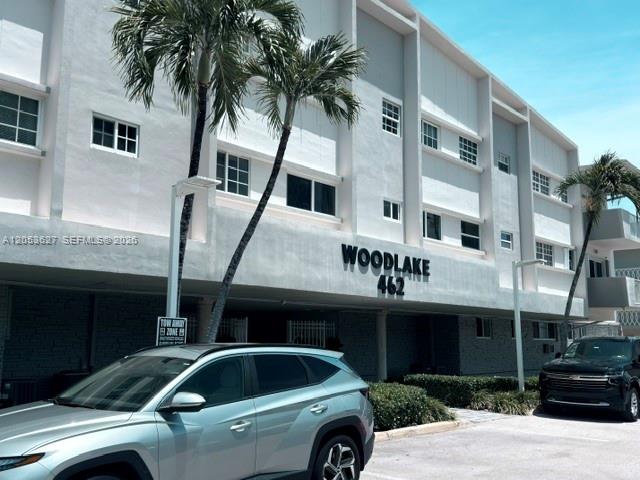 A light-colored multi-story apartment building features palm trees and parked cars in front — 462 Golden Isles Dr # 203, Hallandale Beach FL 33009, HALLANDALE BEACH, FL