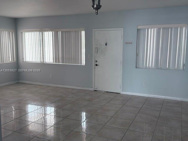 A room with light blue walls, tiled flooring, vertical blinds on windows, and a white door — 462 Golden Isles Dr # 203, Hallandale Beach FL 33009, HALLANDALE BEACH, FL