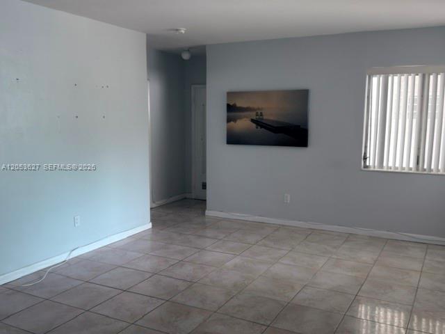 A room with light gray walls, tiled flooring, a window with blinds, and wall art — 462 Golden Isles Dr # 203, Hallandale Beach FL 33009, HALLANDALE BEACH, FL