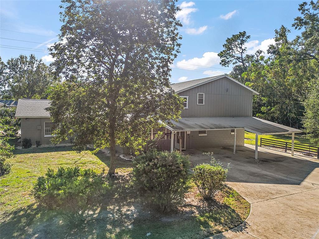A two-story house with a carport, concrete block base, and a large tree in front — 1661 VOTAW ROAD, APOPKA, FL