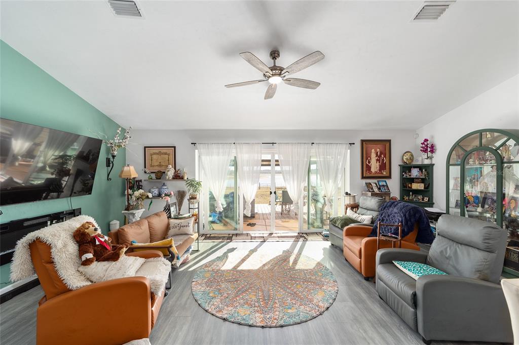 A living room features a ceiling fan, a round rug, and sliding glass doors to a deck — 2120 SE 41ST WAY, TRENTON, FL