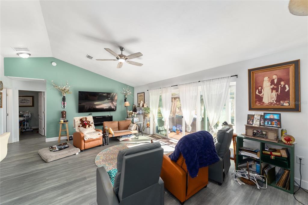 A living room features a vaulted ceiling, a green accent wall, and gray flooring — 2120 SE 41ST WAY, TRENTON, FL