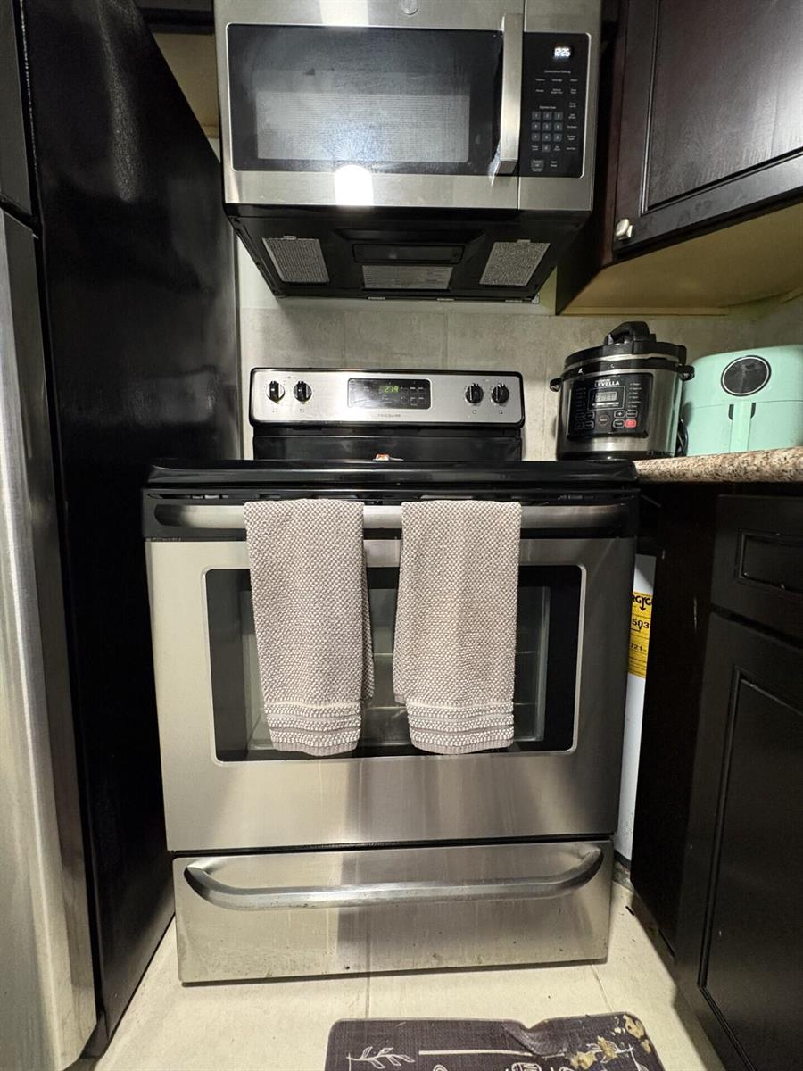 A stainless steel oven and microwave are positioned between a black refrigerator and dark cabinets — 65 Preston B, Boca Raton FL 33434, BOCA RATON, FL