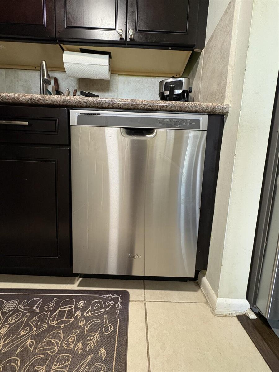 A stainless steel Whirlpool dishwasher is installed under a granite countertop in a kitchen — 65 Preston B, Boca Raton FL 33434, BOCA RATON, FL