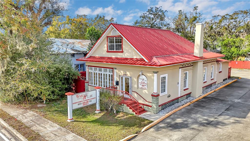 A tan, single-story commercial building with a red metal roof and a prominent corner sign — 1007 EMMETT STREET, KISSIMMEE, FL