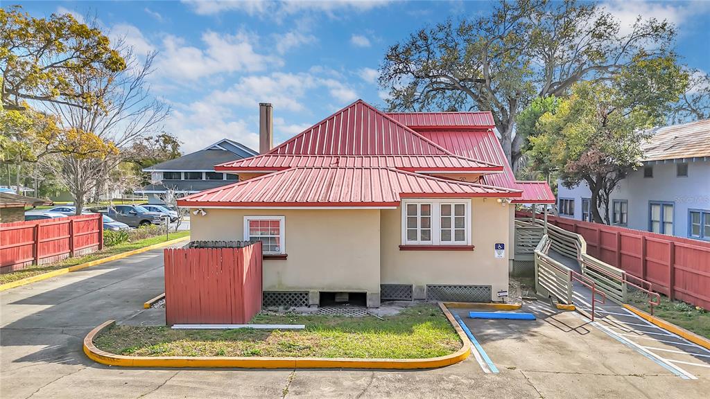 The exterior of a tan building with a red metal roof and a wheelchair ramp — 1007 EMMETT STREET, KISSIMMEE, FL