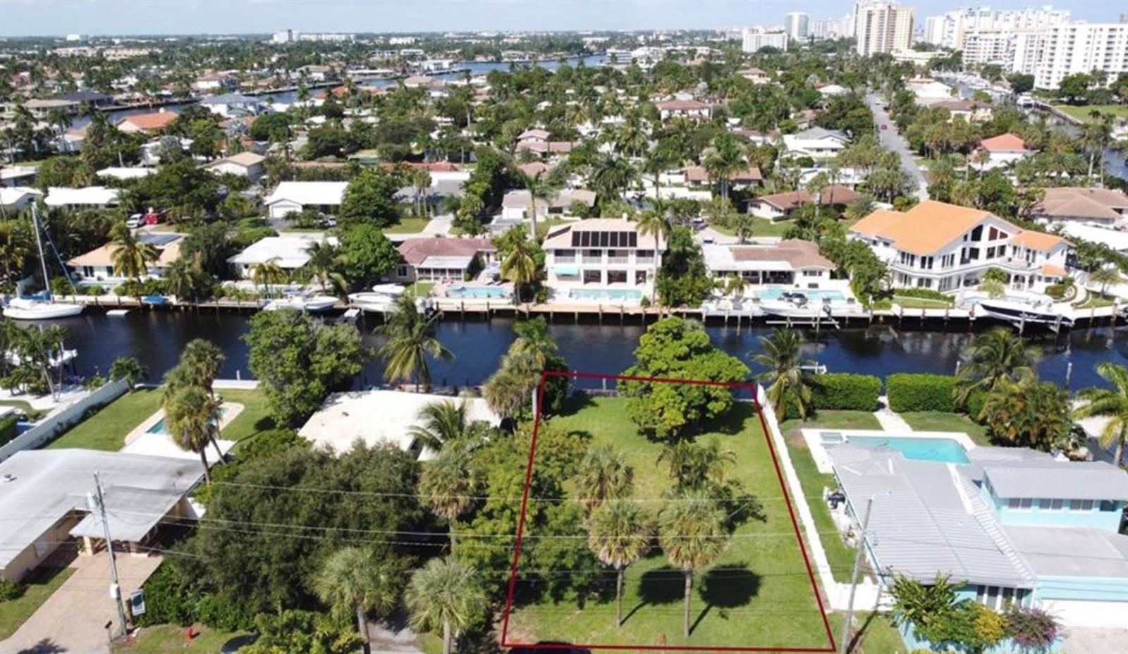 An aerial view shows a vacant, grassy waterfront lot outlined in red between two houses — 5 Sunset Lane, Pompano Beach FL 33062, POMPANO BEACH, FL