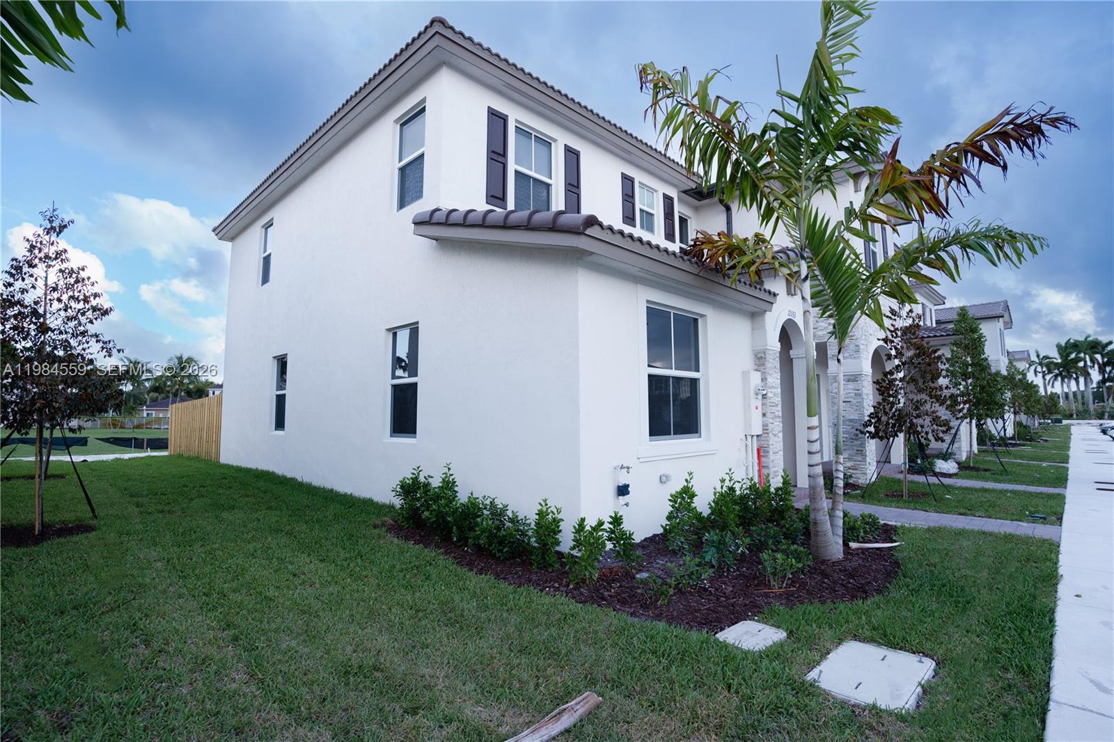 A two-story white stucco house features dark shutters, a tiled roof, and a palm tree — 12133 NW 23rd Ct, Miami FL 33167, MIAMI, FL