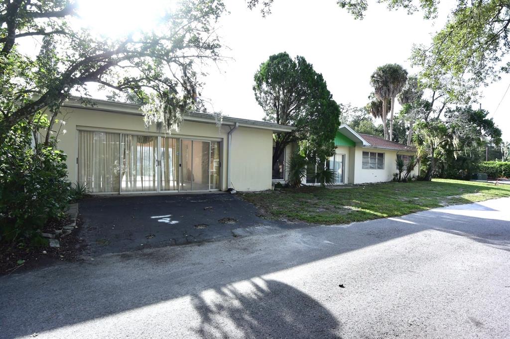 A single-story house with a flat roof, sliding glass doors, and a paved driveway — 7124 JASMIN DRIVE, NEW PORT RICHEY, FL