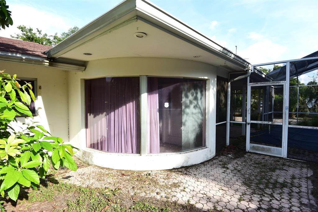 A curved exterior wall with large windows sits beside a screened-in patio area — 7124 JASMIN DRIVE, NEW PORT RICHEY, FL