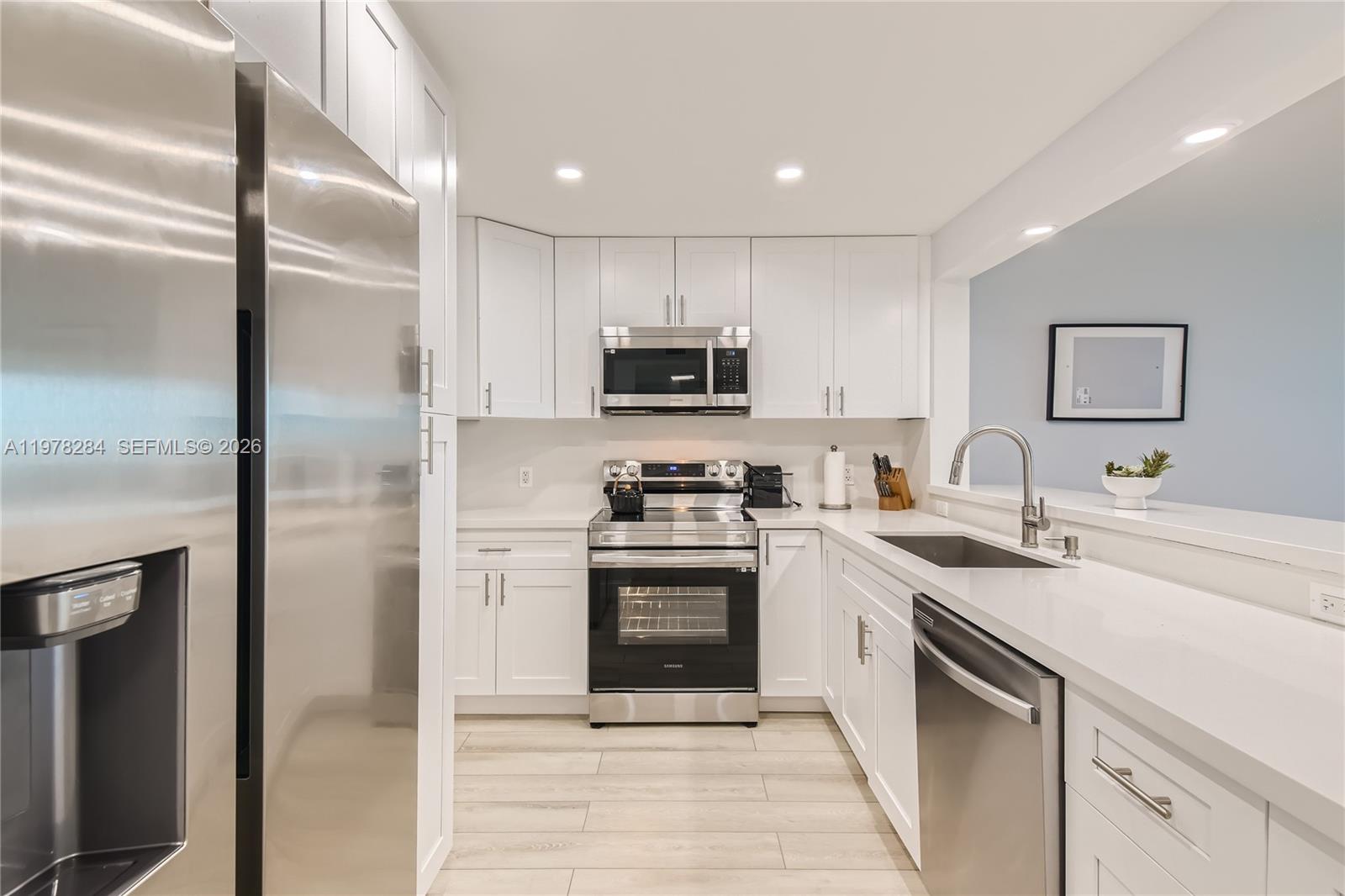 A modern kitchen features white cabinets, stainless steel appliances, and light-colored flooring — 3800 S Ocean Dr, Hollywood FL 33019, HOLLYWOOD, FL