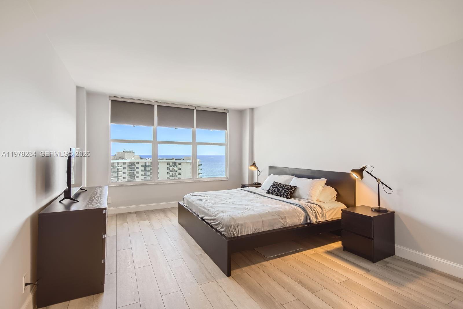 A bedroom features a dark wood bed frame, matching nightstands, and a view of the ocean — 3800 S Ocean Dr, Hollywood FL 33019, HOLLYWOOD, FL