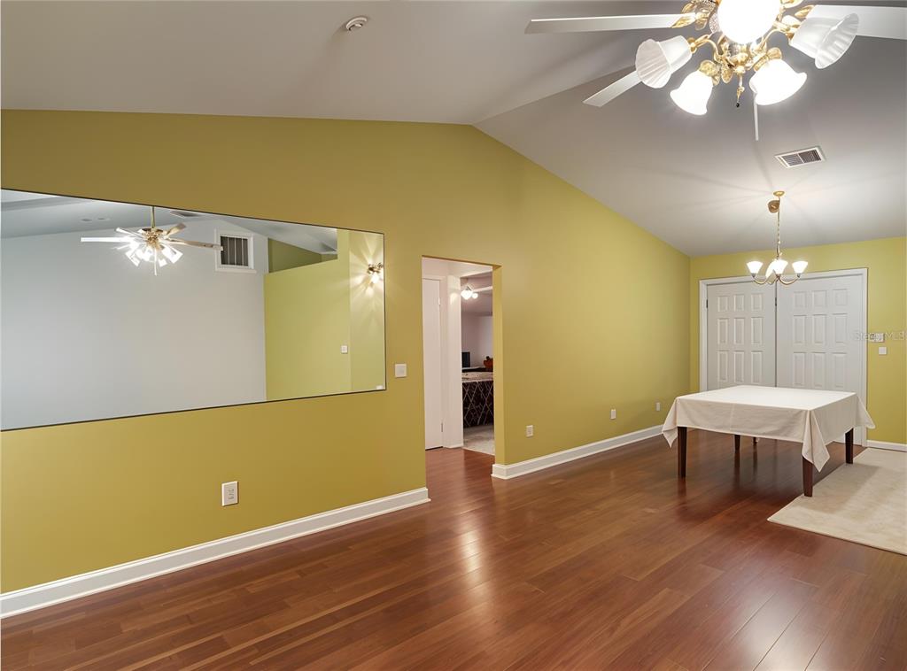 A dining room with hardwood floors, a large wall mirror, and a vaulted ceiling — 912 NE 144TH COURT, SILVER SPRINGS, FL