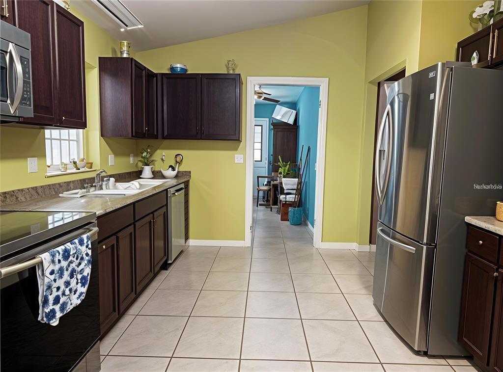 A kitchen features dark wood cabinets, stainless steel appliances, and light green walls — 912 NE 144TH COURT, SILVER SPRINGS, FL