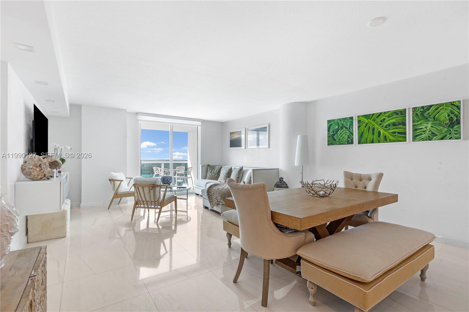 A bright, open-concept living and dining area features white tile floors and a balcony view — 2101 Brickell Ave # 1206, Miami FL 33129, MIAMI, FL