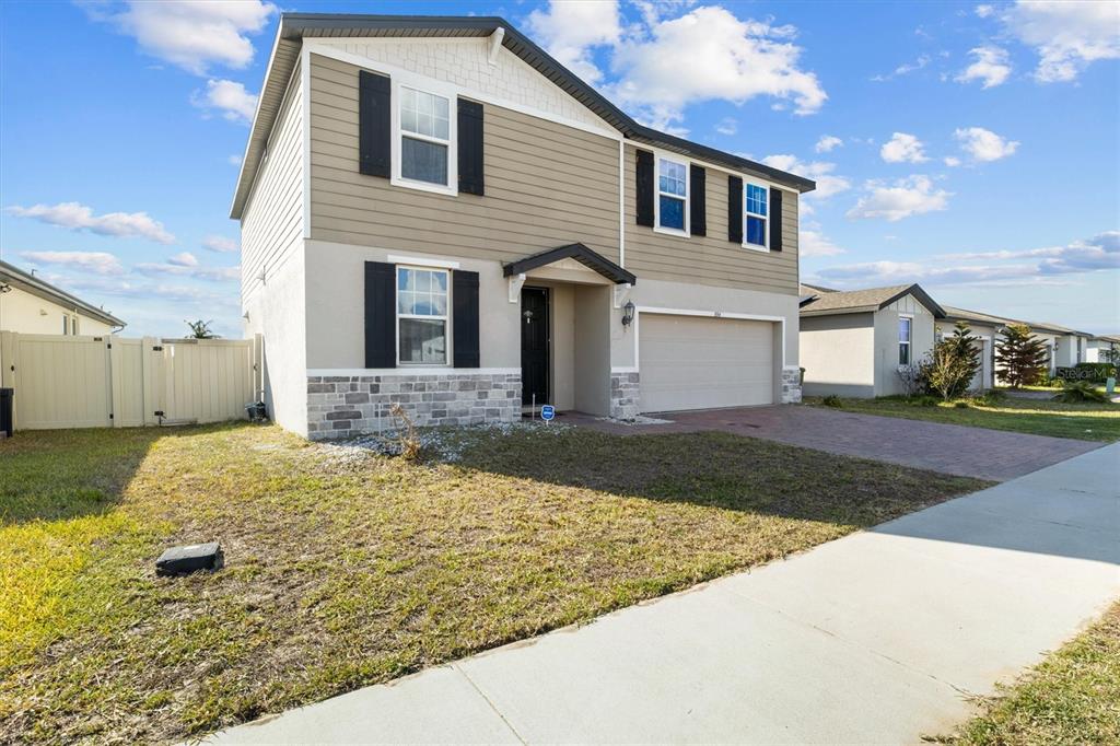 A two-story suburban house with tan siding, stone accents, and a two-car garage — 884 CAMBRIDGE DRIVE, WINTER HAVEN, FL