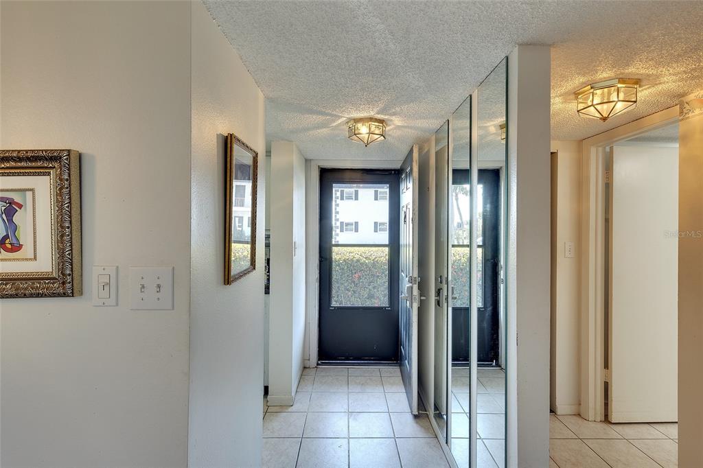 A tiled entryway features a black front door, mirrored closet doors, and two ceiling lights — 305 47TH AVENUE DRIVE W UNIT 146, BRADENTON, FL