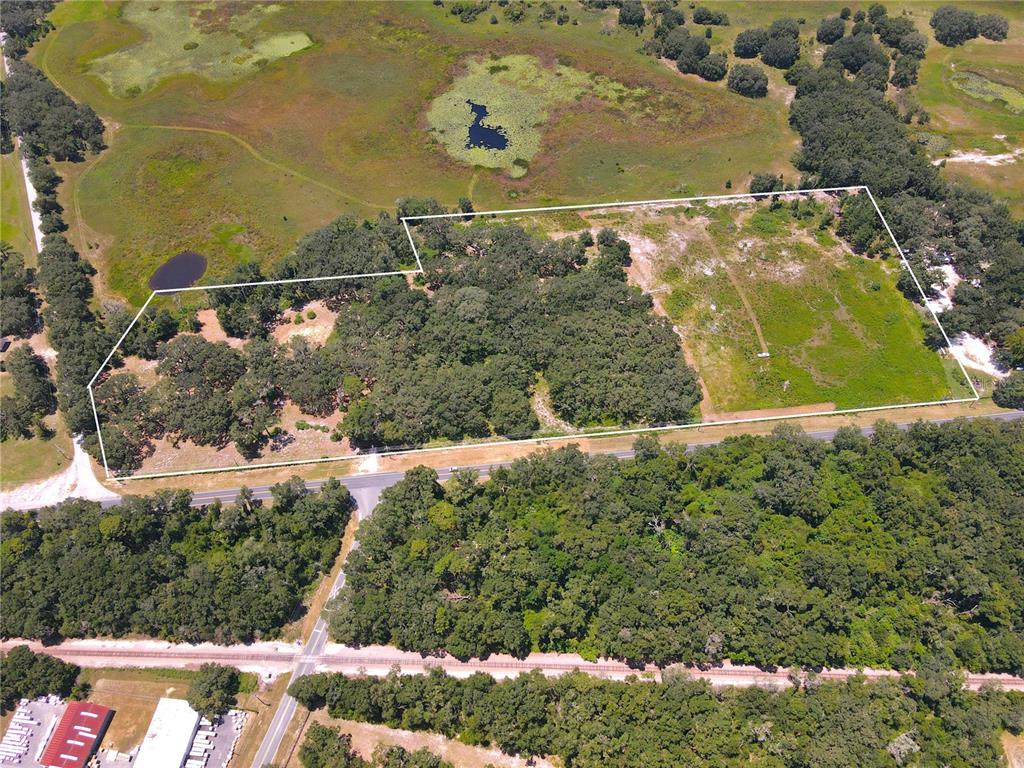 An aerial view shows a rectangular plot of land outlined in white, featuring trees and grass — 1220 N US HIGHWAY 41, DUNNELLON, FL