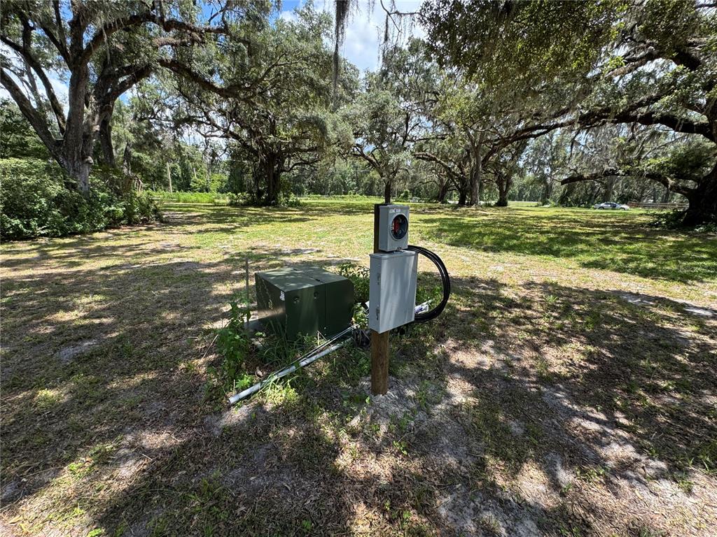 An electrical service pole and utility box stand in a grassy, tree-shaded outdoor lot — 1220 N US HIGHWAY 41, DUNNELLON, FL