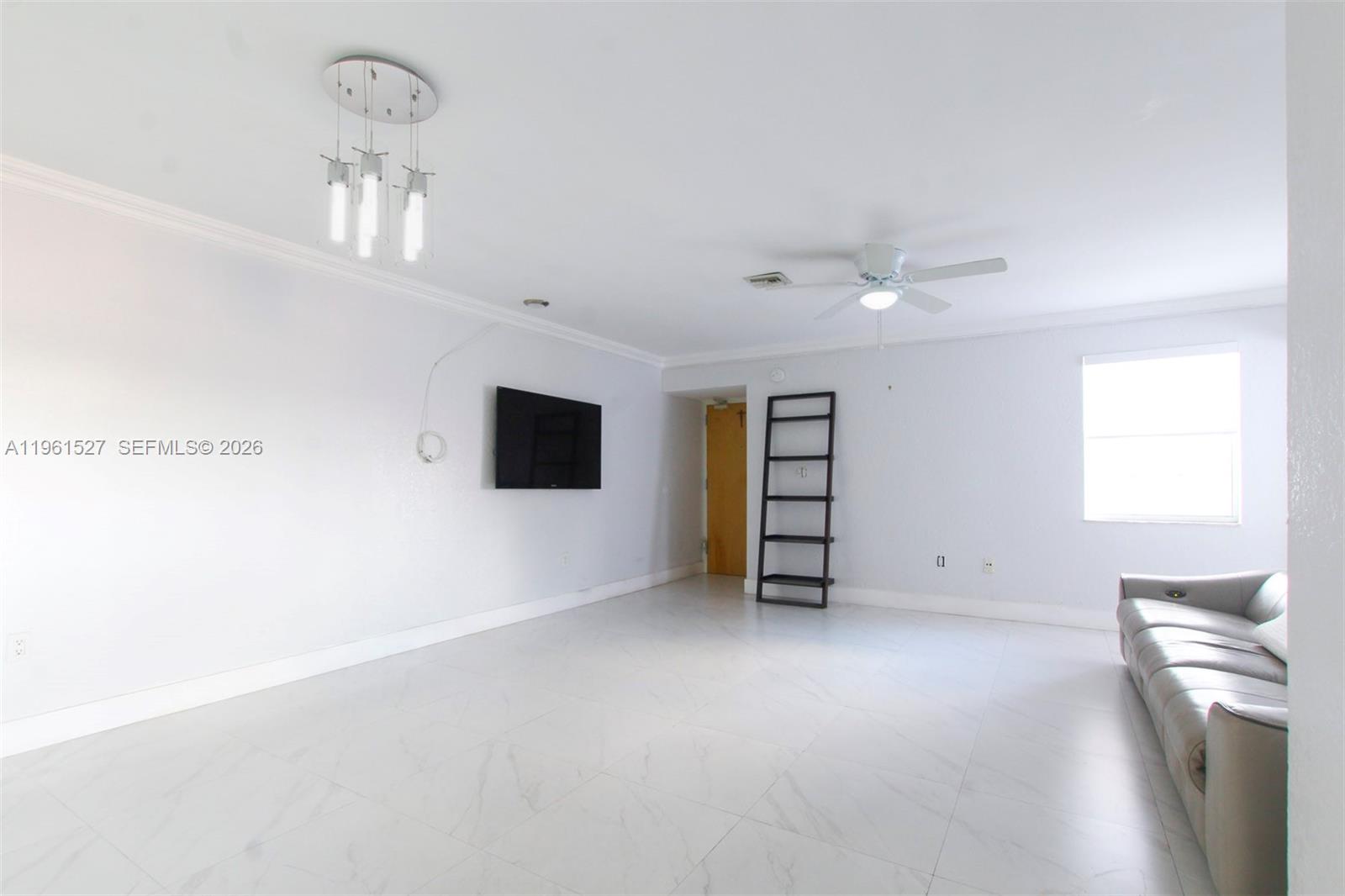 A living room features white tile flooring, a wall-mounted television, and a light-colored sofa — 49 Majorca Ave # 303, Coral Gables FL 33134, CORAL GABLES, FL