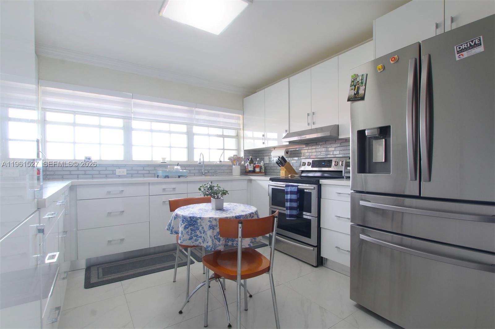 A kitchen with white cabinets, stainless steel appliances, a small round table, and tiled floors — 49 Majorca Ave # 303, Coral Gables FL 33134, CORAL GABLES, FL