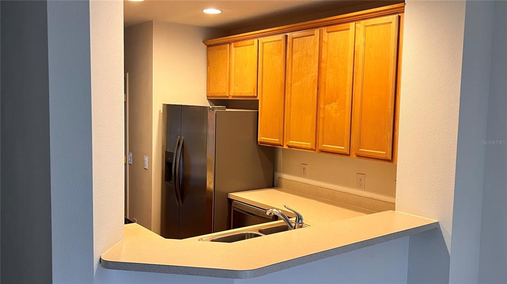 A kitchen features light wood cabinets, stainless steel appliances, and light-colored wood-look flooring — 3514 VICTORIA PINES DRIVE UNIT 148, ORLANDO, FL