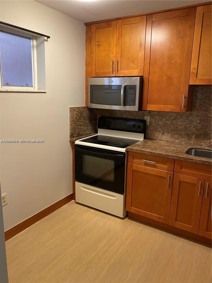A kitchen features wood cabinets, a microwave, a stove, and a stone countertop — 11307 SW 200th St # B, Miami FL 33157, MIAMI, FL