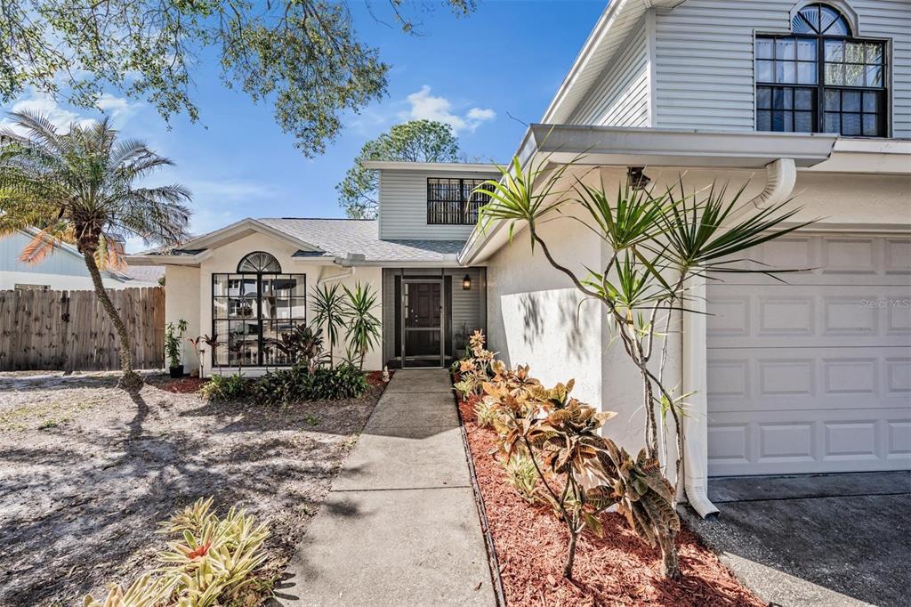 The exterior of a two-story house features a concrete walkway, a garage, and landscaping — 12604 RAIN FOREST STREET, TEMPLE TERRACE, FL