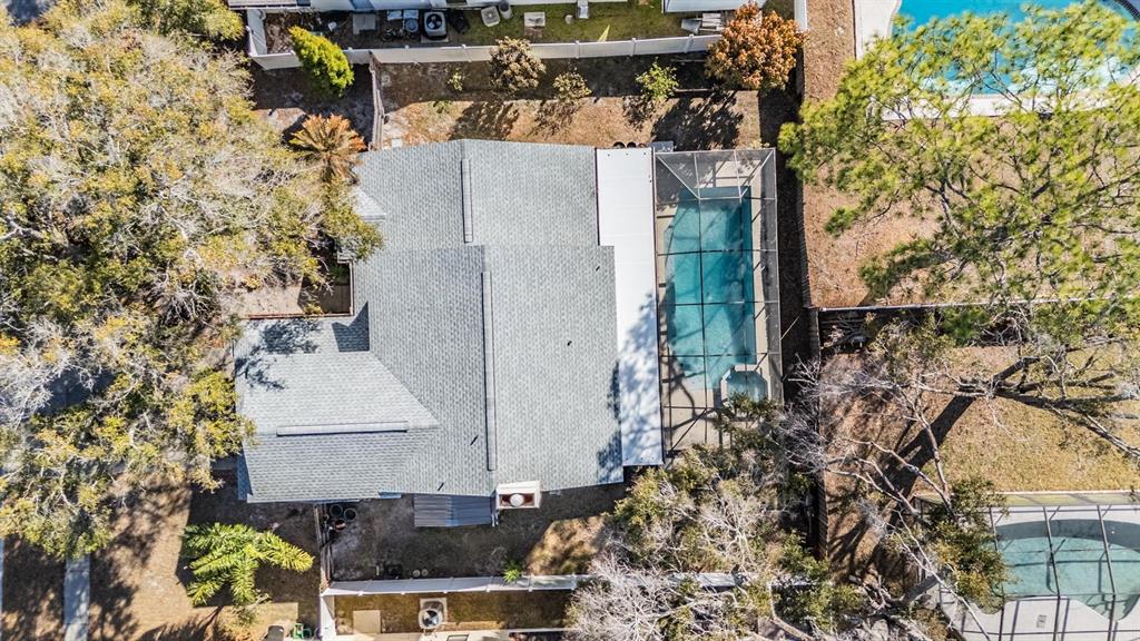 An aerial view shows a house with a grey shingled roof and a screened pool — 12604 RAIN FOREST STREET, TEMPLE TERRACE, FL
