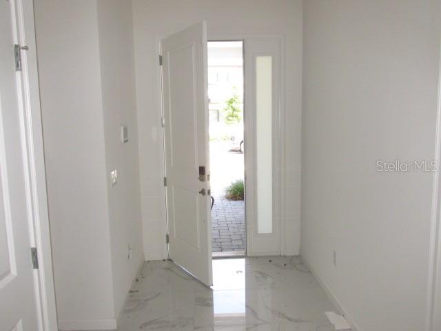An open front door reveals a view of a paved walkway from a tiled entryway — 1275 BUTTERFLY ORCHID ROAD, DAVENPORT, FL