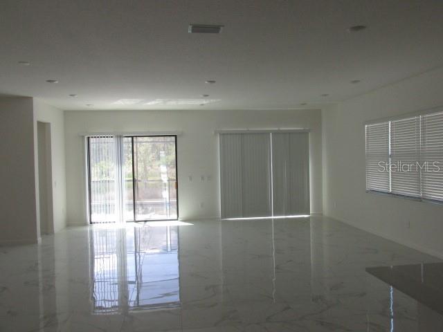 An open living area features white marble-look tile flooring, recessed lighting, and sliding glass doors — 1275 BUTTERFLY ORCHID ROAD, DAVENPORT, FL
