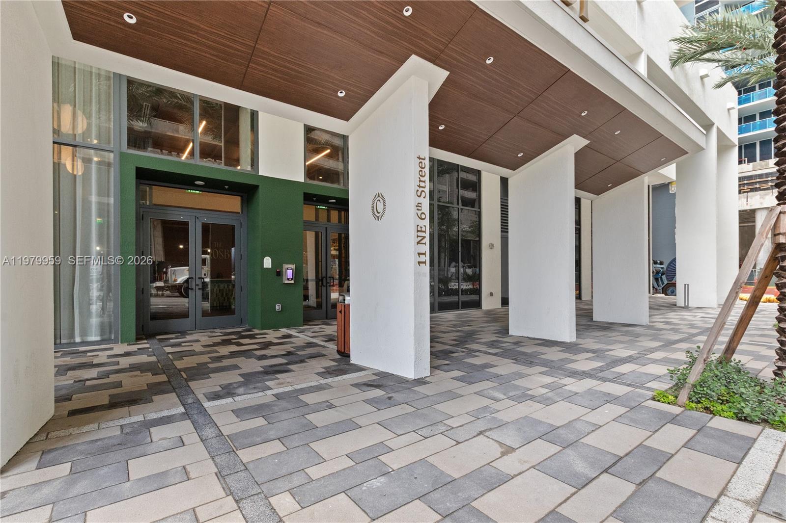 The exterior entrance features a paved walkway, white pillars, and a wood-paneled ceiling — 11 NE 6 ST # 910, Miami FL 33132, MIAMI, FL