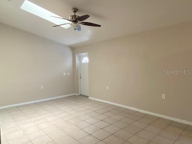 An empty room features beige walls, light-colored tile flooring, a ceiling fan, and a door — 2780 CYPRESS DRIVE UNIT B, CLEARWATER, FL
