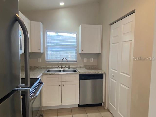 A kitchen features white cabinets, stainless steel appliances, a double sink, and tile flooring — 2780 CYPRESS DRIVE UNIT B, CLEARWATER, FL
