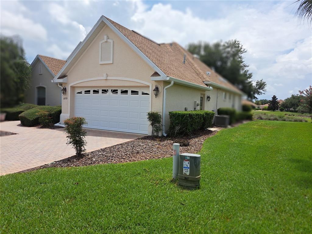 A beige house with a two-car garage and a paved driveway sits on a lawn — 8779 SW 83RD CIRCLE, OCALA, FL