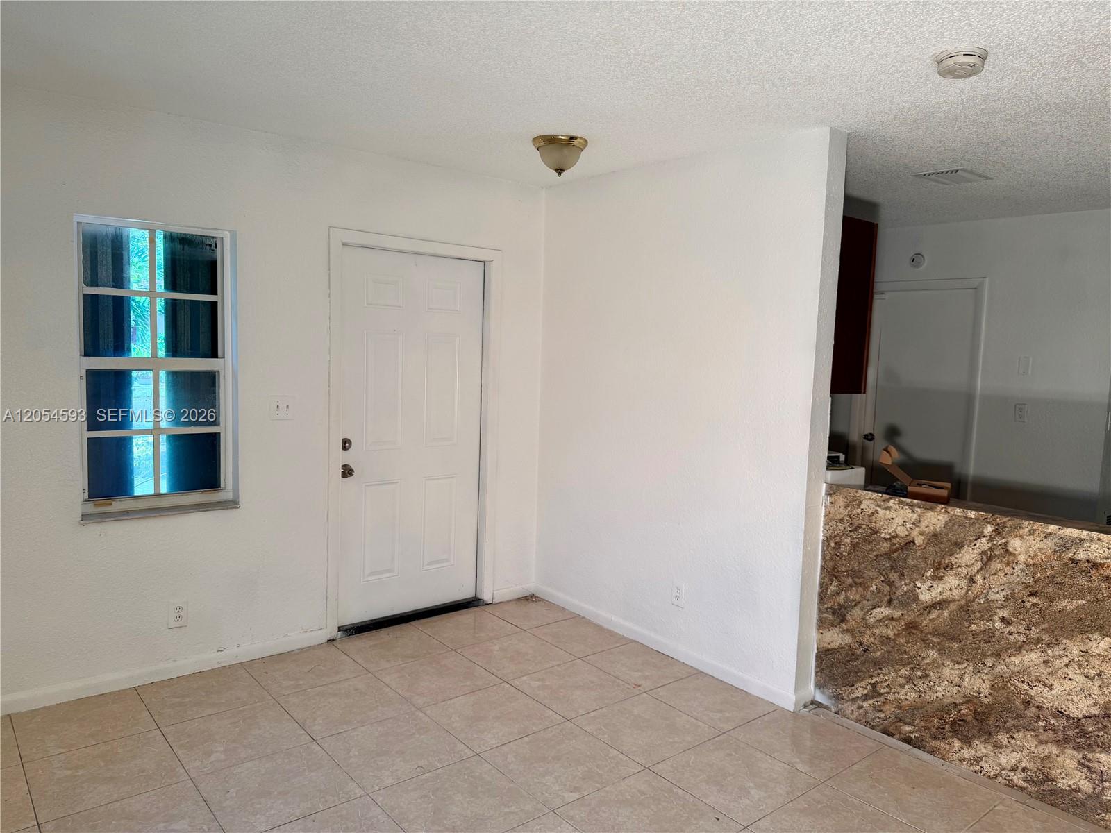 An interior view shows a tiled room with a white door, window, and granite countertop — 1561 NW 7th Ter, Pompano Beach FL 33060, POMPANO BEACH, FL
