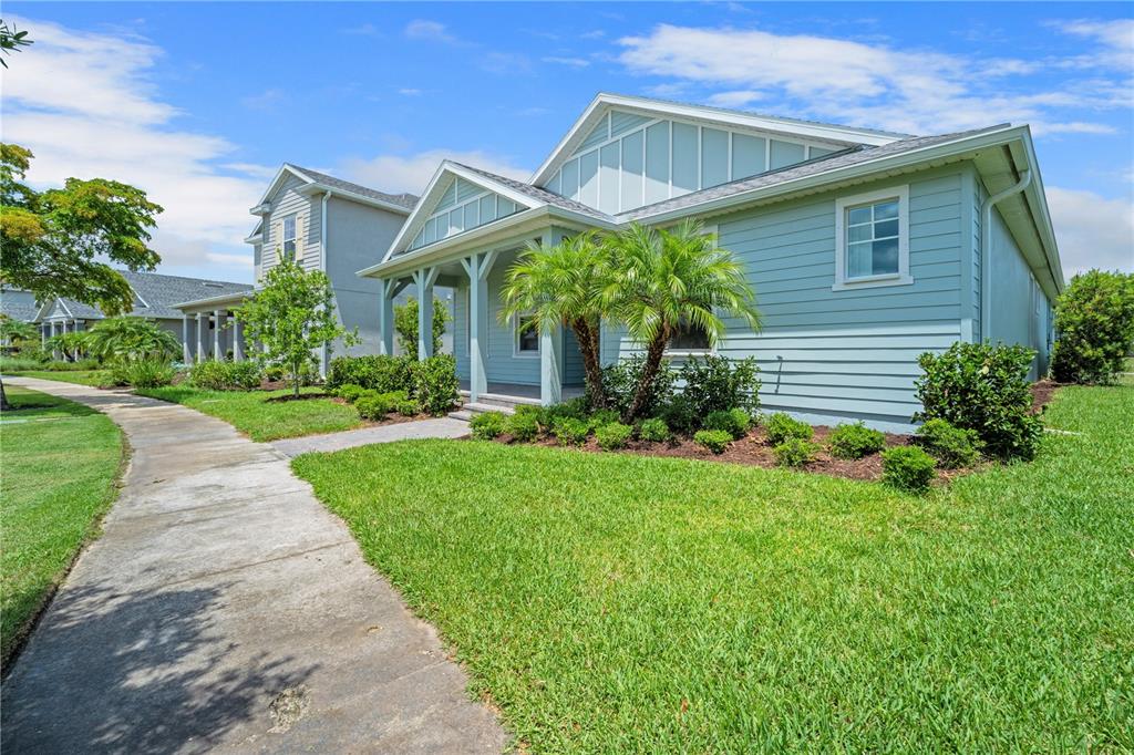 A light blue, single-story house with a covered front porch and a concrete sidewalk — 17057 PINE LILY LANE, PUNTA GORDA, FL