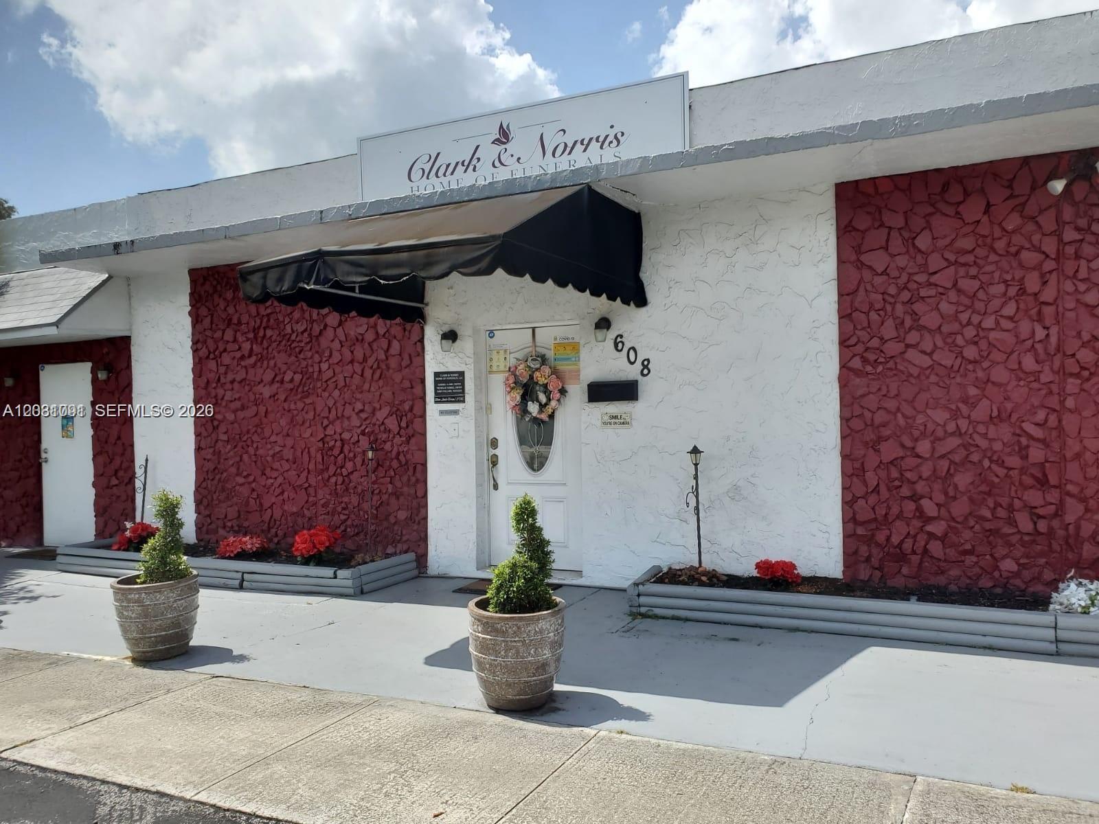 The exterior of a funeral home features red stone accents, a black awning, and potted plants — 608 SW 12th Ave, Dania Beach FL 33004, DANIA BEACH, FL