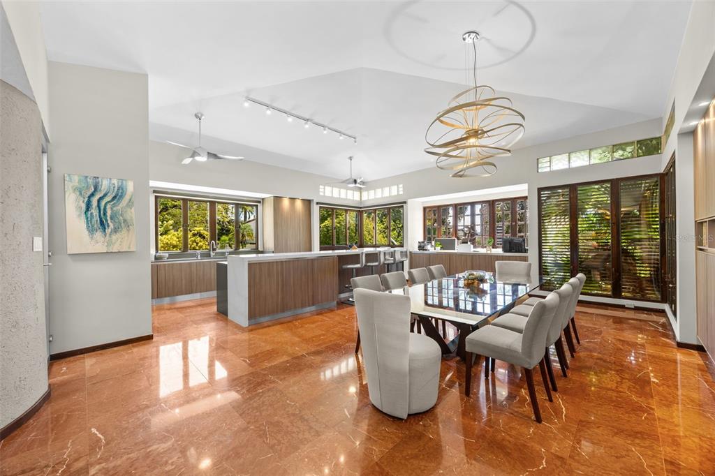 A dining area and kitchen with orange marble floors, a glass table, and modern lighting — H A 28  VILLA CAPARRA, GUAYNABO, PR