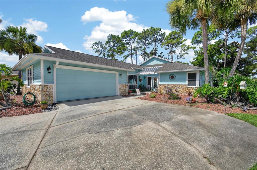 A light blue single-story house with a stone facade, two-car garage, and a concrete driveway — 8 JASMINE RUN, ORMOND BEACH, FL