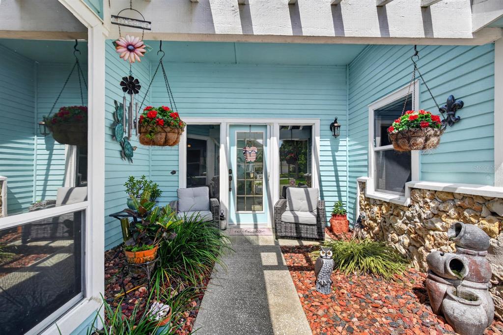 A light blue house exterior features a front porch with two chairs and hanging plants — 8 JASMINE RUN, ORMOND BEACH, FL