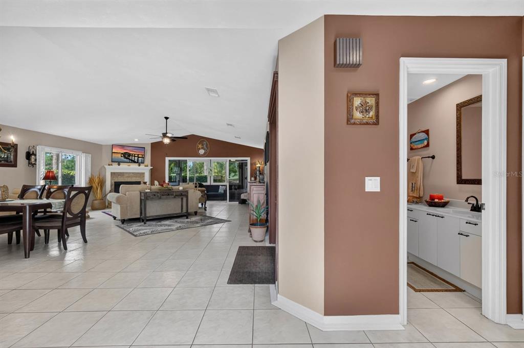 A view from a tiled hallway looking into a living room with a fireplace — 8 JASMINE RUN, ORMOND BEACH, FL