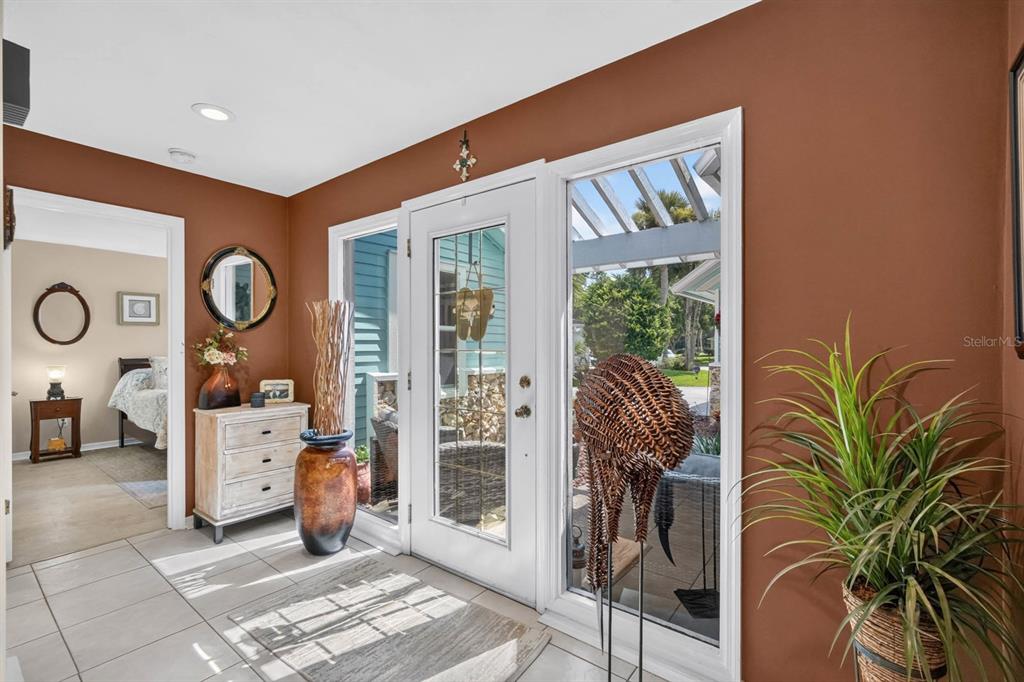 An entryway with terracotta walls, tile flooring, a white front door, and a side room — 8 JASMINE RUN, ORMOND BEACH, FL