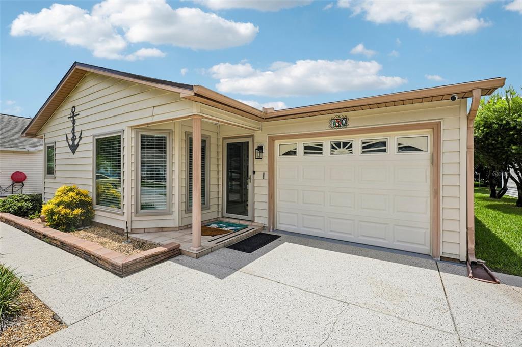 A single-story house with beige siding, a front-facing garage, and a small covered entryway — 710 CORTEZ AVENUE, THE VILLAGES, FL