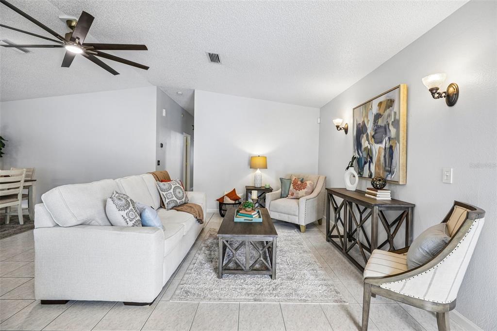 A living room features a white sofa, a coffee table, and an accent chair — 710 CORTEZ AVENUE, THE VILLAGES, FL