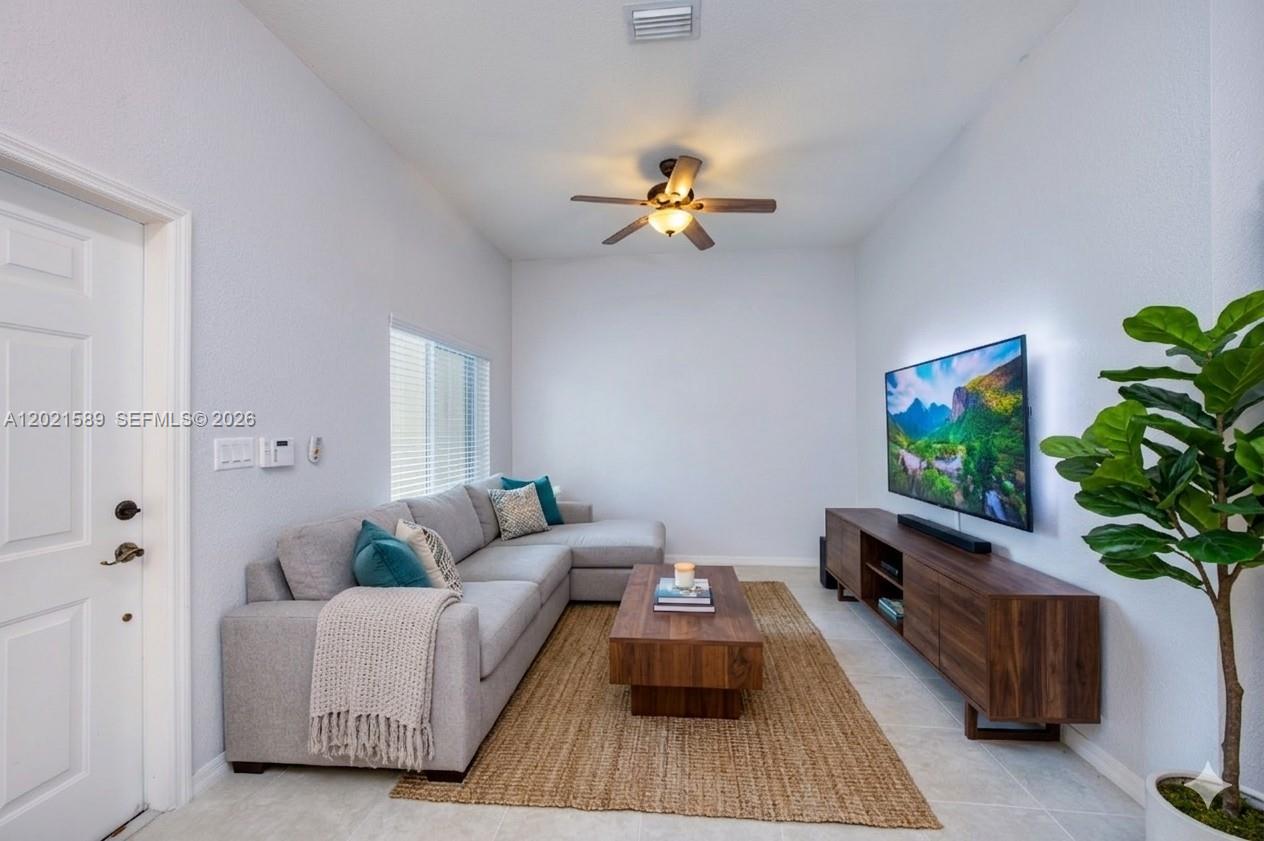 A living room features a gray sectional sofa, a wooden coffee table, and a wall-mounted television — 2343 SE 16th Pl, Homestead FL 33035, HOMESTEAD, FL