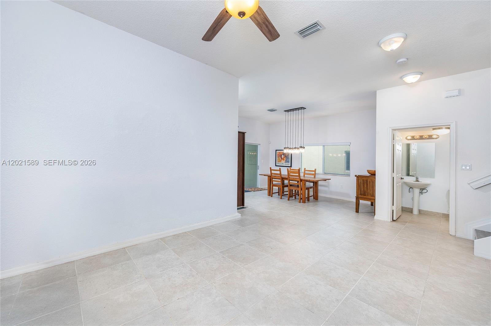 A spacious dining area features tile flooring, a modern chandelier, and an adjacent half bathroom — 2343 SE 16th Pl, Homestead FL 33035, HOMESTEAD, FL